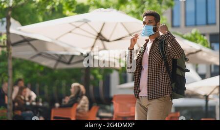 Portrait of happy young man taking off face mask outdoors in city, covid-19 concept. Stock Photo