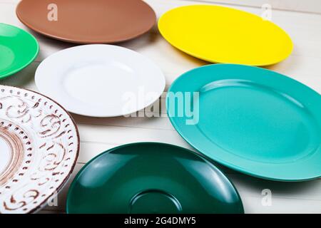 Empty multicolored plates on a wooden background, top view. Stock Photo
