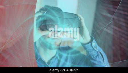 Neon blue digital wave over man wearing vr headset against red technology background Stock Photo