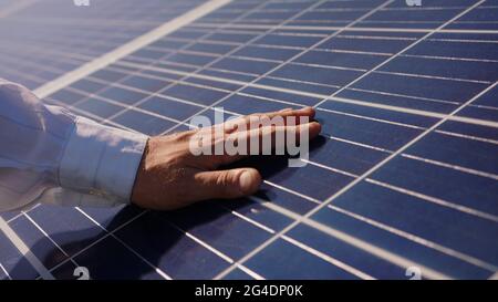 Close up of a young engineer hand is checking the operation of sun and cleanliness of photovoltaic solar panels on a sunset. Concept.renewable energy Stock Photo