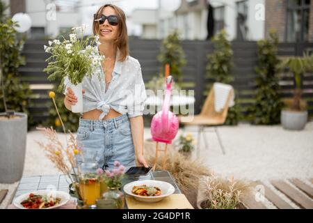 Portrait of a young woman decorating dining table at the backyard of her house. Beauty and aesthetics in everyday life Stock Photo