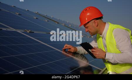 Caucasian man technician using laptop computer checking Solar Cell panels. Engineer repair and maintenance photovoltaic Stock Photo