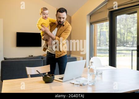 Father nursing his baby son and works from home Stock Photo