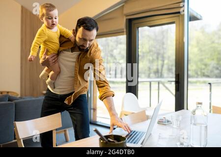 Father nursing his baby son and works from home Stock Photo
