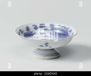 . Porcelain tazza on a high, spreading foot, painted in underglaze blue. On the flat a Ruyi motif in a medallion. The wall with four flower branches (Prunus, Peony, Lotus, Chrysanthemum). Dot the outer wall with groups. Three blue lines on the foot. Cracking porcelain in blue and white. Stock Photo
