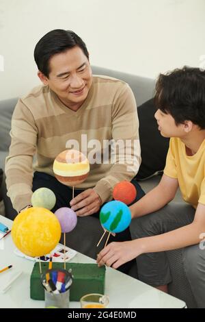 Father and son enjoying spending time together and doing Solar System model for school Stock Photo