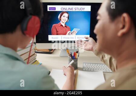 Father helping son to install application for online studying on computer Stock Photo