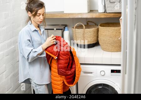 Young housewife looks on a down jacket before washing Stock Photo