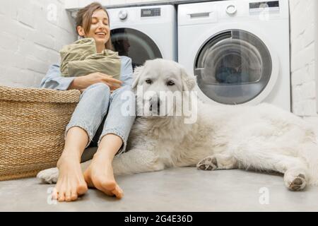 Woman with a dog doing housework in the laundry Stock Photo