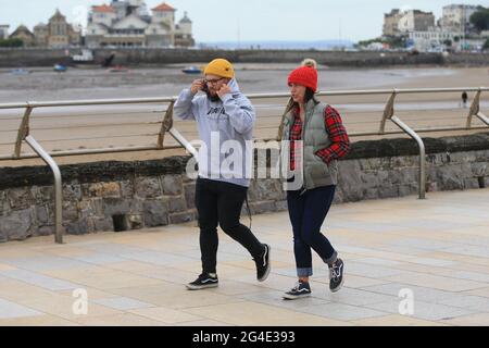 Weston Super Mare, UK, 21st June, 2021. UK Weather.An overcast afternoon with a cool wind as peopple wrap up warm along the promenade in North Somerset on the longest day of the year. Credit: Gary Learmonth / Alamy Live News Stock Photo