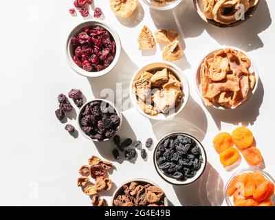 Various dried fruits and berries. Flat lay dried or sun-dried berries and fruits in bowls on white background with shadows. Vegan healthy natural snac Stock Photo