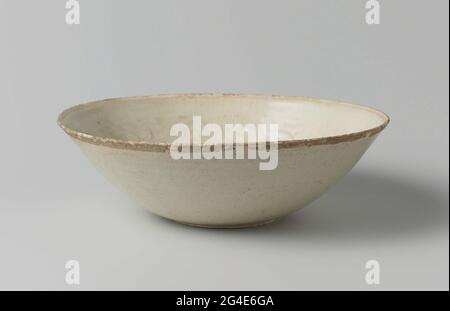 . Wide bowl of stoneware, covered with a crackled, transparent glaze with a light blue hue. A stylized lotus flower in relief on the bottom. The inner wall with a wide bond with floral drinks containing two feng hues in it; above a decorative bond with a geometric motif. A crack in the edge. Qingbai. Stock Photo