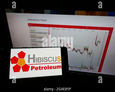 Person holding cellphone with logo of Malaysian company Hibiscus Petroleum Berhad on screen in front of business webpage. Focus on phone display. Stock Photo
