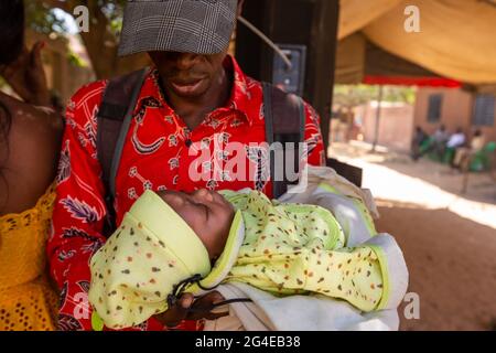 MBOUR, SENEGAL - DECEMBER Circa, 2020. Newborn black african baby on the arm of his father, Dressed for bapteme day. Stock Photo