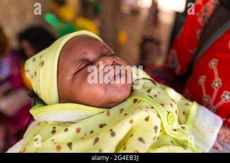 MBOUR, SENEGAL - DECEMBER Circa, 2020. Newborn black african baby on the arm of his father, Dressed for bapteme day. Stock Photo