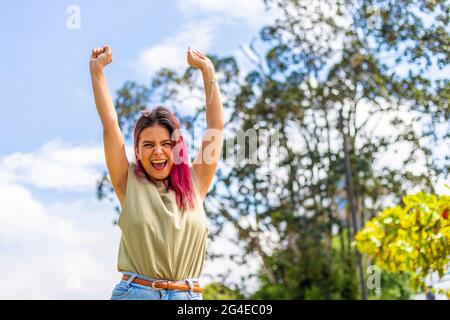 young latin woman celebrating with her hands up in the air Stock Photo
