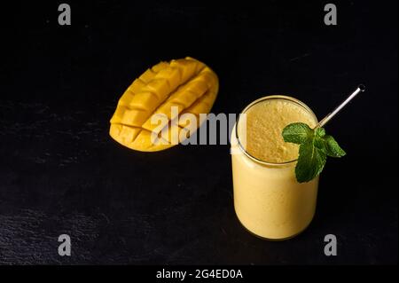 Lassi drink is smoothies or milkshake on dark background. Traditional Indian and Pakistan refreshing with yogurt, mango, spices, mint and ice Stock Photo