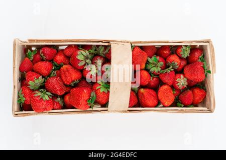 Wooden box full of red ripe strawberries isolated on white background, photographed directly from above. Harvesting summer fruits Stock Photo