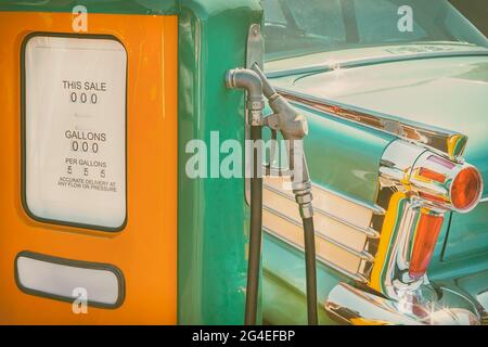 Retro styled image of an old fuel pump and green classic car Stock Photo