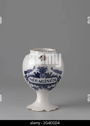 . Pharmacist spot from blue painted faience with inscription: o / mucaginum. The pot stands on a foot, has an ear and a spout. The pot has been marked: LPK. Stock Photo