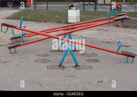 Picture of a kids teeter totter in a playground, empty, with a focus on the seating. A seesaw (also known as a teeter-totter or teeterboard) is a long Stock Photo
