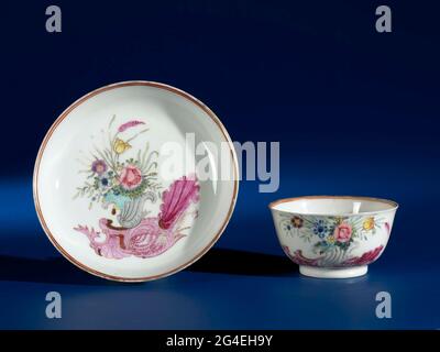 . Bell-shaped cup and saucer of porcelain, painted on the glaze in blue, red, pink, green, yellow, black and gold. On the platter of the dish a European shell ornament with a shell-shaped vase with blooming plants. The head with the same decoration, with a flower branch. Two cracks in the wall of the dish. European performance in email colors. Stock Photo