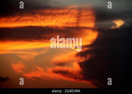 Beautiful colors in the sky as the sun sets behind a large cloud Stock Photo