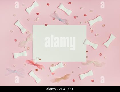 Sheet of paper on Pink paper background with ribbons and beads. Flat lay, top view. Flat lay composition with copy space. Stock Photo