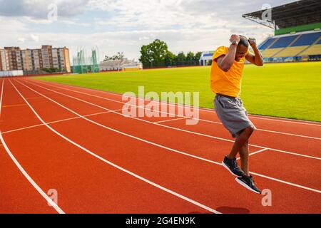 Joyful Afro American runner in yellow sportswear happily jumping and winning the runner competition, receiving first place, training and working hard Stock Photo