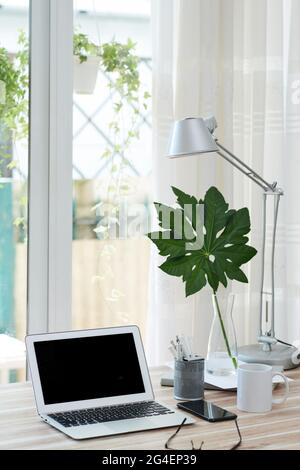 Laptop with black empty screen, cup of coffee and smartphone of table in home office of person Stock Photo
