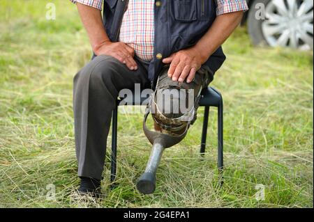 Vintage wooden prosthetic limb of disabled old man sitting on a chair Stock Photo