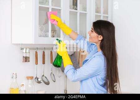 Muslim young woman cleaning shelfs at home at kitchen Stock Photo
