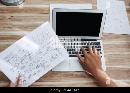 Hands of entrepreneur checking general idea chart and entering infomation in from on laptop, view from above Stock Photo