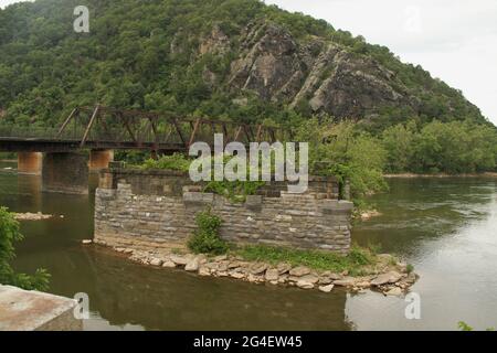 Harpers Ferry, WV, USA. The ruined pylons of the 1850 Bollman Bridge in the Potomac River. Winchester and Potomac Railroad Bridge in the back. Stock Photo