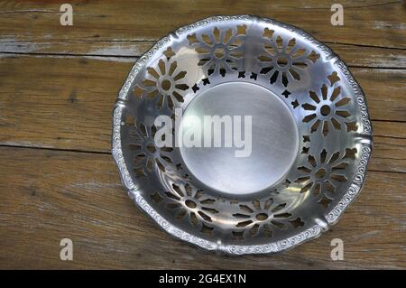 Tray or Fruit Bowl or centerpiece in antique aluminum in stainless steel all lacy and embossed, vintage and retro on wooden background with copy space Stock Photo