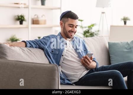 Closeup of smiling jewish man using smartphone at home Stock Photo