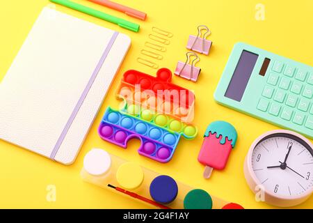 Close up of stationery, clock and silicone toy popit on yellow background Stock Photo