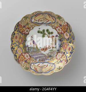 . Painted porcelain plate. The board is a faithful copy of an Imari example. On the flat is a bird on a rock, painted on the edge a busy decor of flowers, in which two six-spectant fields are saved with a bird in it. The plate has been marked. Stock Photo