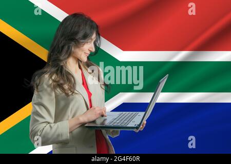 Freelance in South African Republic. Beautiful young woman freelancer uses laptop computer against the background of the flag of South African Republi Stock Photo