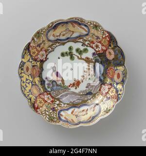 . Painted porcelain plate. The board is a faithful copy of an Imari example. On the flat is a bird on a rock, painted on the edge a busy decor of flowers, in which two six-spectant fields are saved with a bird in it. The plate has been marked. Stock Photo