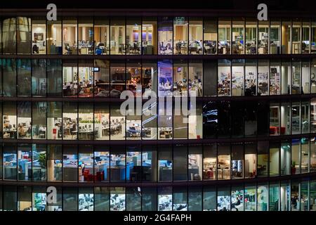 Office windows at night with people working Stock Photo