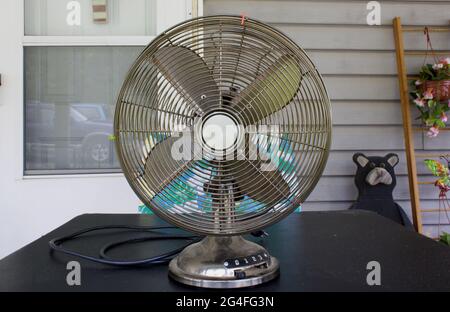 An Old Style Oscillating Fan on a Table Outdoors Stock Photo