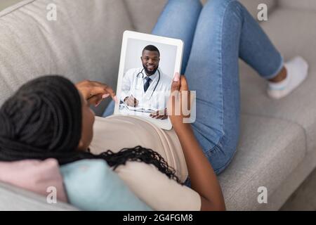 Young black woman having online appointment with doc, using pad Stock Photo