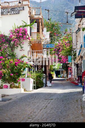 A narrow cobbled street in Kalkan, Turkey, with overhanging balconies coverd in Bougainvillea.  Kalkan is a popular holiday destination and is located Stock Photo