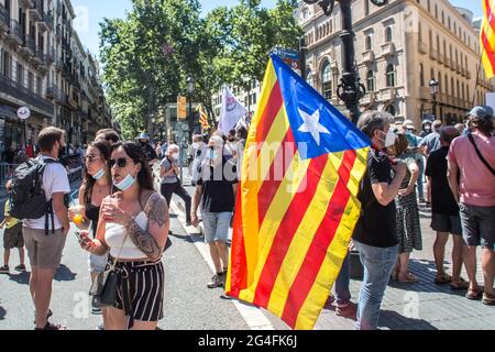 June 21, 2021, Barcelona, Catalonia, Spain: Women are seen passing through a Catalan independence demonstration.Hundreds of Catalan independentistas have demonstrated this Monday, June 21, in Las Ramblas in Barcelona, in front of the Gran Teatre del Liceu (Great Theater of the Lyceum), shielded by many policemen, to protest the visit of the President of the Spanish Government, Pedro Sanchez, who has held a conference entitled ''Reunion: a project for the future for all of Spain'', with the expectation of an imminent granting of pardons for the independence leaders in prison. The protesters pro Stock Photo
