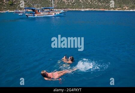 Kalkan, Turkey, 2020. Two young ladies swimming in the sea near to moored charter yachts in a sheltered part of Kalkan bay in Turkey;  located on the Stock Photo
