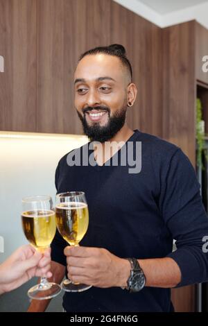 Portrait of handsome bearded man clinking glasses with girlfriend when they are celebrating anniversary at home Stock Photo