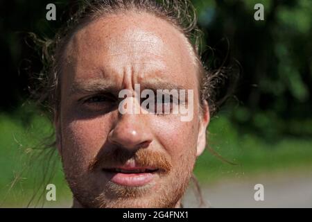 Umea, Norrland Sweden - June 4, 2021: man who is dazzled by strong sunlight Stock Photo