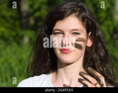 Muddy Face of a Young Long Haired Brunette Caucasian Woman Outdoors on a Sunny Summer Day Stock Photo