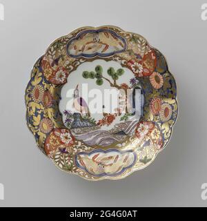 . Painted porcelain plate. The board is a faithful copy of an Imari example. On the flat is a bird on a rock, painted on the edge a busy decor of flowers, in which two six-spectant fields are saved with a bird in it. The plate has been marked. Stock Photo